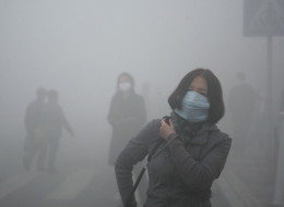 A woman wearing a mask walk through a street covered by dense smog in Harbin, northern China, Monday, Oct. 21, 2013. Visibility shrank to less than half a football field and small-particle pollution soared to a record 40 times higher than an international safety standard in one northern Chinese city as the region entered its high-smog season. (AP Photo/Kyodo News)