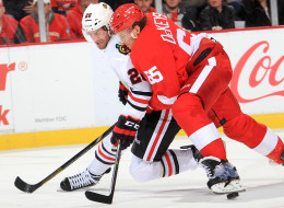 Danny DeKeyser #65 of the Detroit Red Wings bodies Brandon Saad #20 of the Chicago Blackhawks off the puck during an NHL game on January 22, 2014 at Joe Louis Arena in Detroit, Michigan. Detroit defeated Chicago 5-4 in a shootout (Photo by Dave Reginek/NHLI via Getty Images)