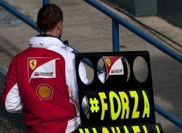 A member of the Ferrari team holds a board with a message of support for seven-time World Champion Michael Schumacher during the Formula One pre-season test days at Jerez racetrack in Jerez on January 29, 2014.