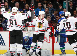 Marian Hossa #81 and Jonathan Toews #19 celebrates a goal by Patrick Sharp #10 of the Chicago Blackhawks against Roberto Luongo #1 of the Vancouver Canucks as Kevin Bieksa #3 of the Canucks turns away during their NHL game at Rogers Arena January 29, 2014 in Vancouver, British Columbia, Canada. Chicago won 5-2. (Photo by Jeff Vinnick/NHLI via Getty Images)