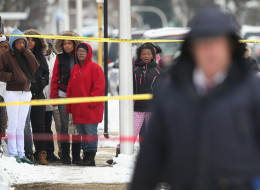 Neighborhood residents watch as police investigate a homicide scene after a 24-year-old man was found dead with a gunshot to his back in the Lawndale neighborhood on December 15, 2013 in Chicago, Illinois. (Photo by Scott Olson/Getty Images)