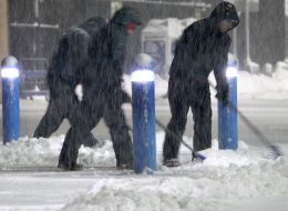 Workers clears snow from the sidewalk outside a business Saturday, Feb. 15, 2014, in the Boston suburb of Hudson, Mass. (AP Photo/Bill Sikes)