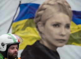 An anti-government protester stands in front of a portrait of jailed former Ukrainian Prime minister Yulia Tymoshenko, on Maidan square in Kiev, on February 13, 2014. Ukraine has been in chaos since November when President Viktor Yanukovych ditched an EU trade and political pact in favour of closer ties with Moscow, its former Soviet master. AFP PHOTO / MARTIN BUREAU (Photo credit should read MARTIN BUREAU/AFP/Getty Images)