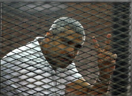 Canadian-Egyptian journalist Mohamed Fahmy gestures from the defendant's cage during a sentencing hearing in a courtroom in Cairo, Egypt, Monday, June 23, 2014. An Egyptian court on Monday convicted three journalists from Al-Jazeera English and sentenced them to seven years in prison each on terrorism-related charges, bringing widespread criticism that the verdict was a blow to freedom of expression. The three, Australian Peter Greste, Canadian-Egyptian Mohammed Fahmy and Egyptian Baher Mohammed