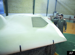 This photo released on Thursday, Dec. 8, 2011, by the Iranian Revolutionary Guards, claims to show US RQ-170 Sentinel drone which Tehran says its forces downed earlier this week, as an unidentified colonel, right, talks to the chief of the aerospace division of Iran's Revolutionary Guards, Gen. Amir Ali Hajizadeh, in an undisclosed location, Iran. (AP Photo/Sepahnews)
