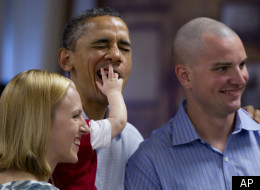 President Barack Obama gets a mouth and face full of fingers from Cooper Wall Wagner, 8 months, as he poses for a photo with Cooper and his parents, Captain Greg and Meredith Wagner, while visiting members of the military during Christmas dinner at Anderson Hall on Marine Corps Base Hawaii, Sunday, Dec. 25, 2011, in Kaneohe, Hawaii. (AP Photo/Carolyn Kaster)