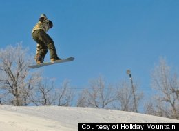 A snowboarder catches some air on the slopes of Holiday Mountain.