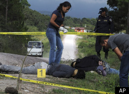 In this Wednesday Oct. 5, 2011 photo, the bodies of three people, who police allege are gang members who were killed by unidentified assailants, are inspected by a forensic team in the village of Los Hornos, Honduras, 20 kilometers (13 miles) south of Tegucigalpa. Honduras has become a main transit route for South American cocaine, a trend that has helped drive the country's homicide rate to the highest level in the world and left many villages dependent on the cocaine trade. (AP Photo/Fernando