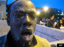 In this photo provided by David Steinman, Nnaemeka Alozie, campaign manager for Steinman, reacts with milk on his face after being sprayed with pepper spray during a protest on Tuesday, April 3, 2012, in Santa Monica, Calif. Campus police pepper-sprayed as many as 30 demonstrators after Santa Monica College students angry over a plan to offer high-priced courses tried to push their way into a trustees meeting Tuesday evening, authorities said. (AP Photo/Courtesy David Steinman)
