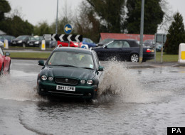 A car drives through a puddle near Epsom, Surrey