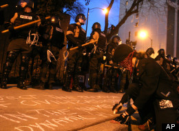 A demonstrater writes a message on the sidewalk in front of Illinois State police officers dressed in riot gear during an anti-war protest along Oak Street, Saturday, March 18, 2006, in Chicago. (AP Photo/Joshua Lott)