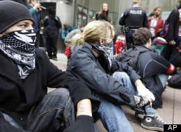 In this May 1, 2012, photo, Occupy Chicago activists block the entrance to a Bank of America branch as part of a May Day demonstration in Chicago. They accuse banks of profiting over the needs of ordinary people and decry Bank of America's federal bailout. Those planning the protests when the NATO Summit comes to Chicago, May 20-21, hope to draw big crowds to the city. (AP Photo/M. Spencer Green)