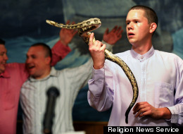 Andrew Hamblin, 21, pastor of Tabernacle Church of God in LaFollette, Tenn., looks into the eyes of a rattlesnake at the church alter while others sing songs during church service on April 13, 2012. RNS photo by Shelley Mays/courtesy USA Today