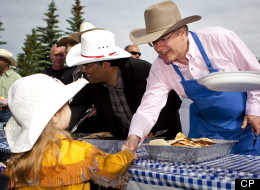 Prime Minister Stephen Harper, right, shakes hands with Ashleigh Budd, four, as he dishes out pancakes at Stampede breakfast in Calgary, Alta., Sunday, July 10, 2011.THE CANADIAN PRESS/Jeff McIntosh