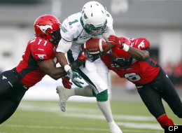 Saskatchewan Roughriders' Kory Sheets, centre, tries to run the ball past Calgary Stampeders' Malik Jackson, left, and Fred Bennett during first quarter CFL football action in Calgary, Alta., Thursday, July 19, 2012. (THE CANADIAN PRESS/Jeff McIntosh)