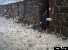 A resident of Footdee stands on a doorstep overlooking a street covered in sea foam.