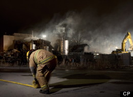An emergency worker rolls up a hose outside Neptune Technologies and Bio Resources in Sherbrooke, Que., Thursday, November 8, 2012 where a large explosion at the plant sent a number of people to hospital with serious injuries. THE CANADIAN PRESS/Graham Hughes.